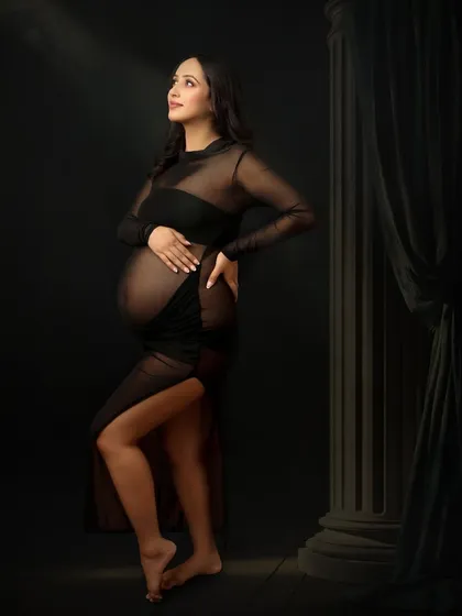 Elegance in every curve. This stunning portrait in a sheer black gown uses dramatic lighting to create a powerful and artistic image against a simple, dark backdrop.