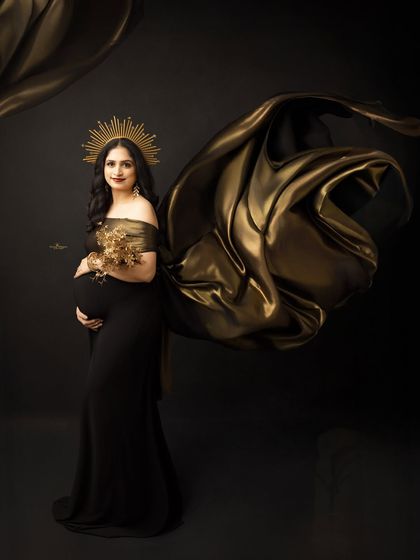 A powerful and regal maternity portrait. The mother-to-be wears a golden sunburst crown and holds a golden bouquet, looking like a true goddess of motherhood.