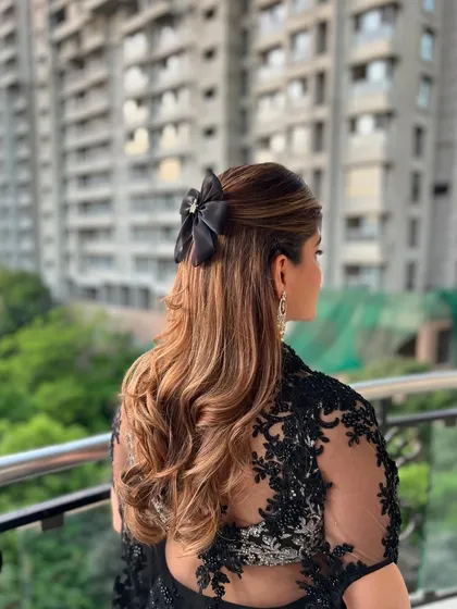 A chic half-up style with soft waves, finished with a stylish black bow accessory. This look is perfect for a cocktail party or a modern reception.