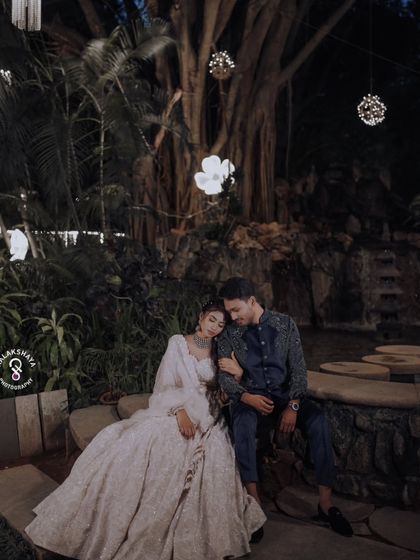 A romantic night-time shot of the couple at their Sangeet, seated under a beautifully lit tree.