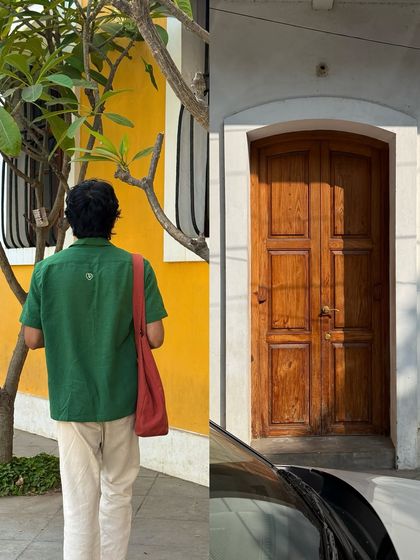 Walking past a classic wooden door set in a white wall, next to the vibrant yellow of a neighboring building in Pondicherry's French Quarter.