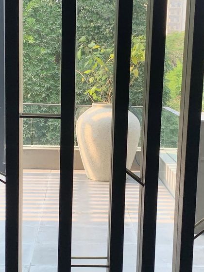 A view through a slatted screen to a large white urn on a terrace. The screen creates a sense of filtered privacy while framing the view, turning a simple object into a deliberate focal point.