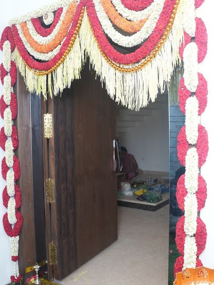 Traditional floral decor for the main door of the house. We used garlands made of red and white flowers to create an intricate and welcoming entryway for the Griha Pravesh ceremony.