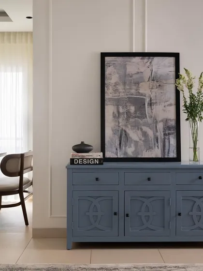 This custom-painted blue credenza serves as a stylish storage solution and an anchor for the entryway. Paired with abstract art, it makes a statement and introduces the apartment's color story right from the start.