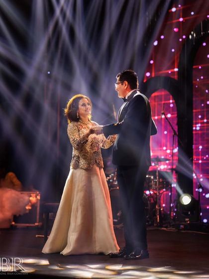 The parents of the bride sharing a romantic moment on stage, with beautiful lighting setting the mood.