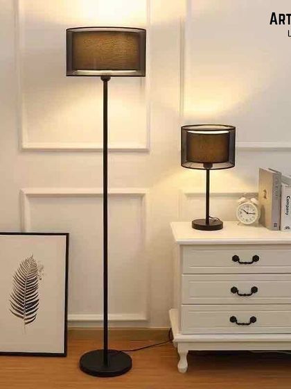 We offer coordinated lighting sets for a cohesive look. This matching floor and table lamp duo features a simple black stand and a double-layered shade, providing an extravagant yet minimalist touch for a modern living area.