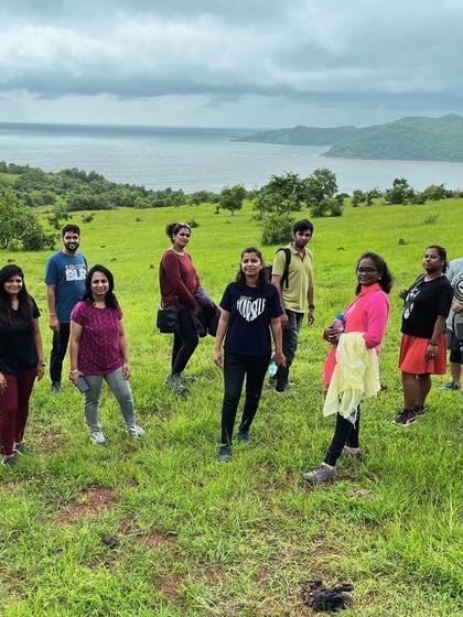 The tribe posing on a grassy cliff overlooking the ocean near Gokarna. This viewpoint offers a stunning contrast between the green land and the blue sea.