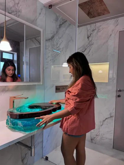 A photo of me with the finished, installed resin and wood washbasin. It's a piece that redefines luxury in a bathroom space.