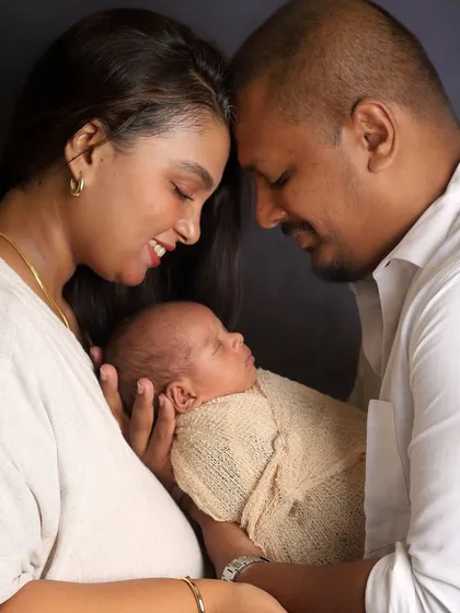 An intimate close-up of new parents with their sleeping baby. This pose, with their heads touching, creates a beautiful sense of unity and love.