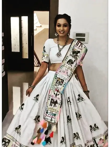 A lovely white georgette lehenga with colorful embroidered animal and bird motifs. The dupatta features a unique embroidered border with playful tassels, making this a fun and distinctive choice for Navratri.