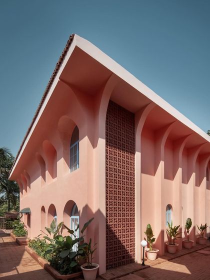 The architecture of Baia Villas is defined by its bold forms and playful use of color. This exterior view showcases the interplay of arches and a terracotta jali screen, elements that nod to Goan heritage while creating a distinctly contemporary facade.