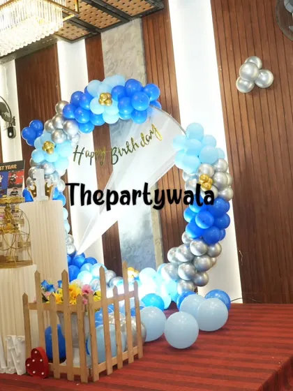 A blue and silver balloon ring set up in a large hall with a high ceiling. The decorations look grand and fill the space beautifully.