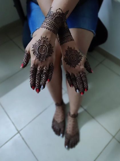 A complete look with matching mehendi on the hands and feet. The hands feature a classic mandala design, while the feet have a delicate pattern, creating a coordinated and polished appearance.