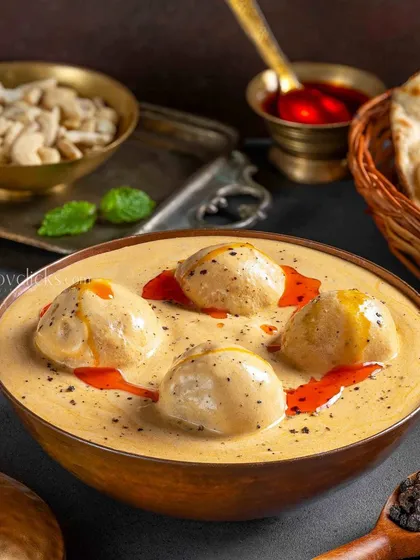 Malai Kofta presented in a creamy white gravy. The subtle garnishes and elegant plating for The Mughal House give this classic dish a refined look.