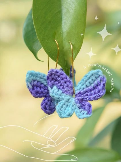 A close-up of the blue and purple 'Titli' earrings. The 100% cotton yarn makes them incredibly lightweight and comfortable.