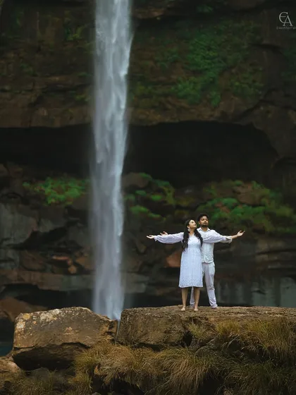 Arms outstretched in a moment of freedom and joy, with the magnificent waterfall as their witness. This pose captures a feeling of epic love and boundless possibilities.