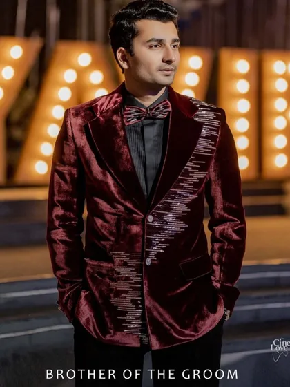The brother of the groom, styled to perfection. For the cocktail evening, we selected this striking burgundy velvet jacket with unique embellishments from Manish Malhotra. It's a look that is both fashionable and sophisticated, allowing him to stand out while complementing the family's overall aesthetic.