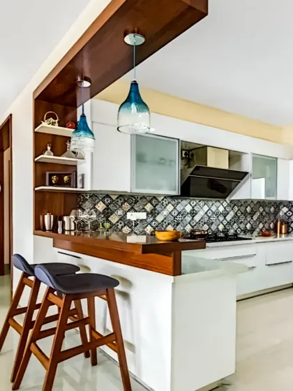 Our modular kitchens combine sleek aesthetics with smart functionality. This design features a stylish breakfast bar with pendant lighting, patterned backsplash tiles, and handleless white cabinets for a clean, contemporary look perfect for modern living.