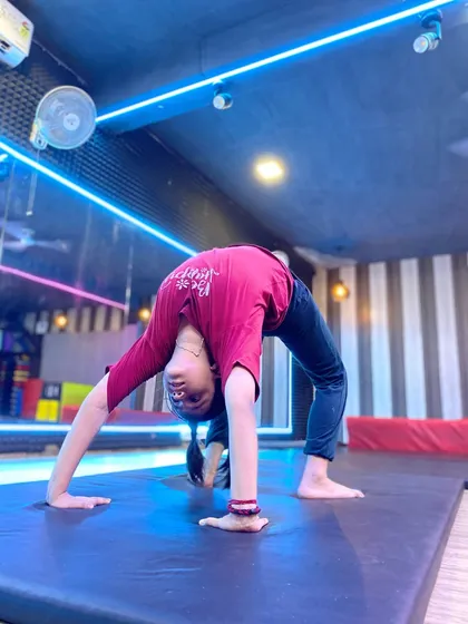 A student performs a perfect backbend on the mat. Notice the even arch in her back, which is a sign of good technique and consistent practice in our flexibility training sessions.