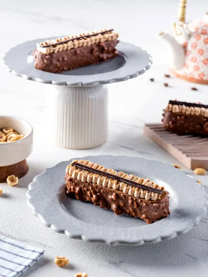 Hazelnut pastries elegantly arranged on scalloped plates and a cake stand. The composition creates a sense of occasion, perfect for showcasing desserts for a special event or high tea.