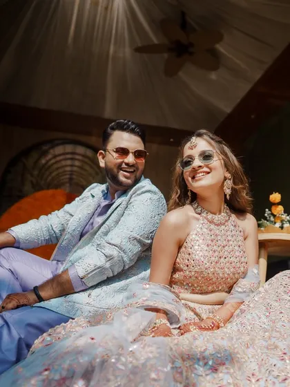 Fun and fresh for the Haldi Carnival. The couple is relaxed and happy in their coordinated pastel outfits, with the bride in a mirror-work lehenga and the groom in a custom lilac kurta set.