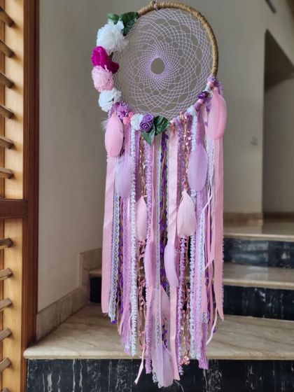 Blossoming dreams. This floral dreamcatcher, with its crescent of flowers and pastel ribbons, is a beautiful and delicate piece of wall decor.