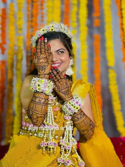 A classic bridal pose, with one hand covering half her face, drawing all attention to the stunning mehndi.