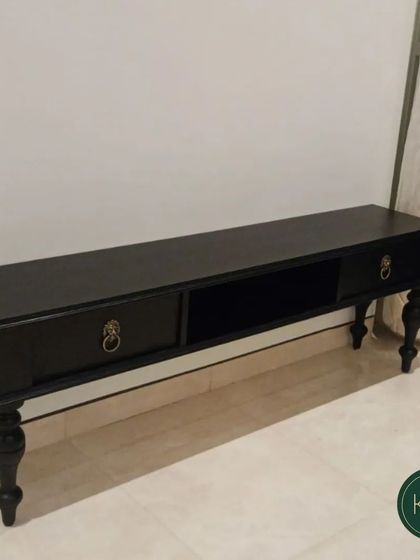 A classic, low-profile TV console in a dark finish with turned legs and antique-style ring pulls. This piece offers a timeless and elegant solution for media storage.