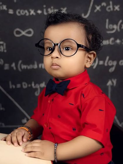 A close-up of a baby boy wearing big glasses, looking very serious about his studies. An adorable and funny shot.