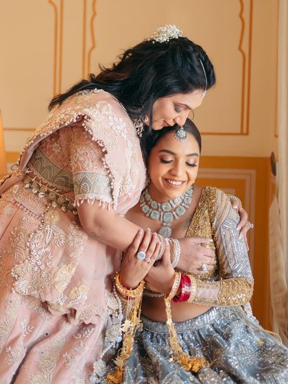 A touching moment between bride Mishi and her mother. Mishi's modern gold and silver lehenga is paired with a clean, luminous makeup look.