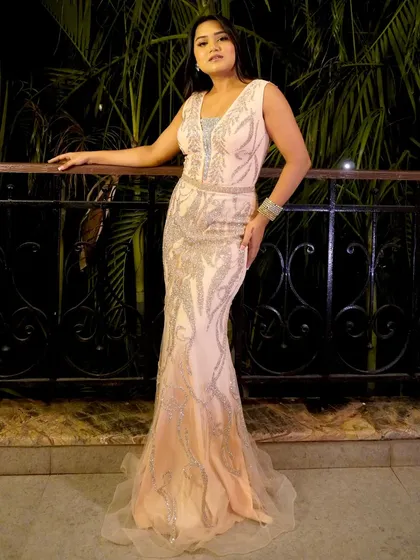 A full-length shot of the peach gown. The mermaid cut and the intricate silver detailing create a very elegant and sophisticated silhouette.