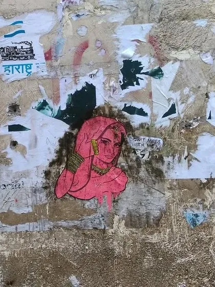 A pink paste-up of a woman in traditional attire with a speech bubble saying "Don't mess with me." This small but feisty piece of art was found on a weathered wall in Mumbai.