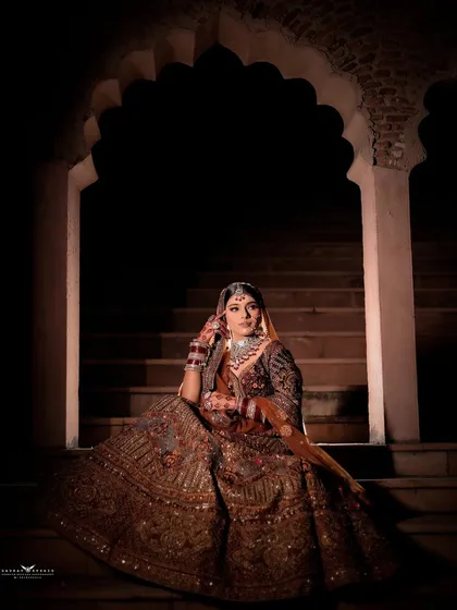 A dramatic portrait of the bride on a staircase, with focused lighting creating a spotlight effect on her.