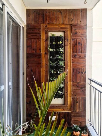 A custom-designed balcony featuring a vertical garden set within a reclaimed wood panel wall. This detail transforms a small outdoor space into a living green feature, bringing nature into a high-rise apartment.