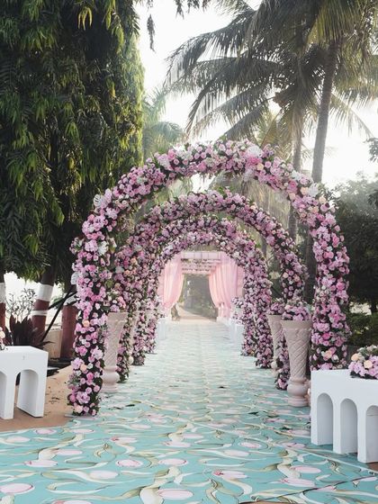A breathtaking floral tunnel made of pink and white roses. This grand entrance creates an immersive and romantic experience for guests as they walk into the wedding venue.