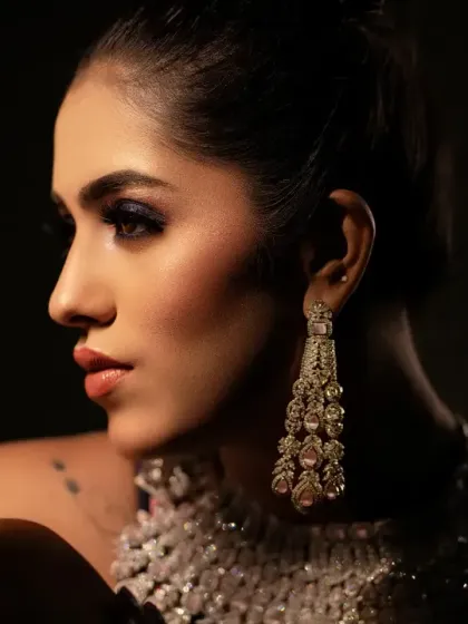 A striking, low-light bridal portrait. The focus is on her profile and the intricate details of her diamond jewelry, creating a moody and glamorous look.