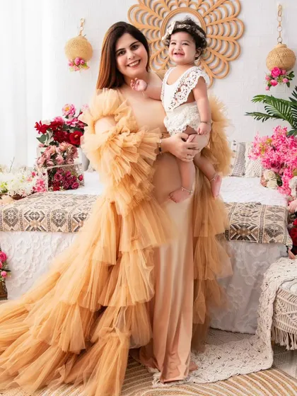 A stunning mother-daughter portrait. The mother's dramatic, ruffled gown complements her daughter's outfit, creating a high-fashion, memorable image.