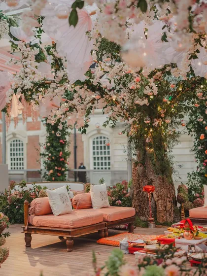 A beautiful seating area under a tree adorned with cherry blossoms and hanging lights. This creates a perfect spot for guests to relax and take photos.