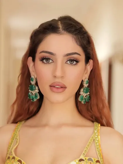 Another look at this radiant model, showcasing the flawless makeup and the striking contrast of the green earrings against her hair.