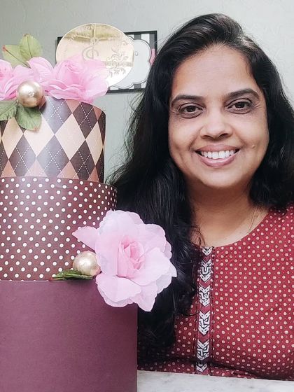 Me with a stylish three-tiered dummy cake featuring different patterns, perfect for display.