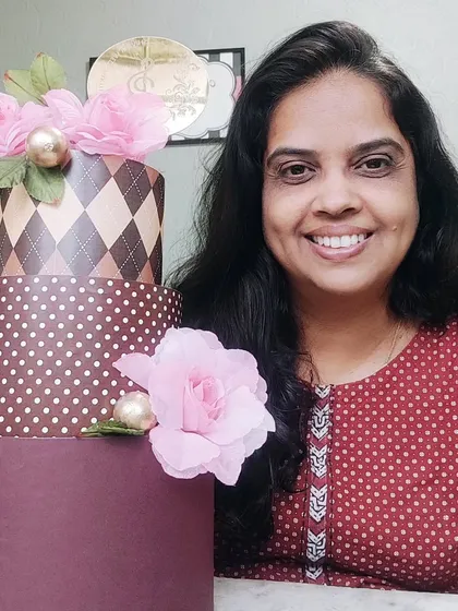 Me with a stylish three-tiered dummy cake featuring different patterns, perfect for display.