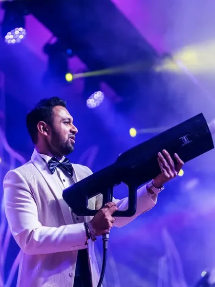 A guest having fun with a CO2 smoke gun on stage. We incorporate interactive elements like this to elevate the party atmosphere and ensure the Sangeet is a high-energy, memorable experience for everyone.