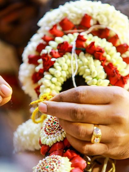 A detailed shot of the groom's hands tying the sacred floral garland, a small but significant part of the wedding ceremony.