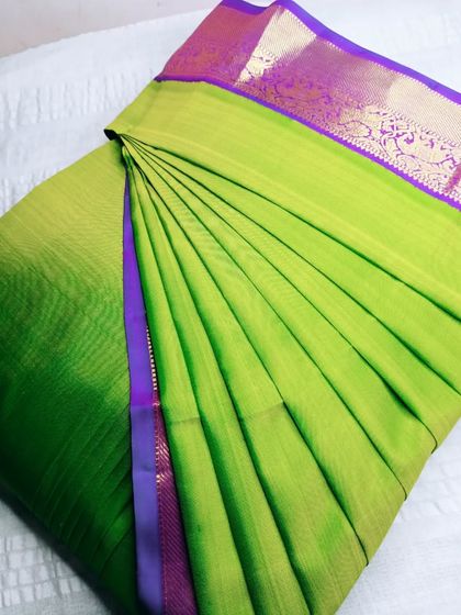 A parrot green saree with a purple border. The pleats are crisp and the colors are vibrant, making it a perfect choice for any celebration.