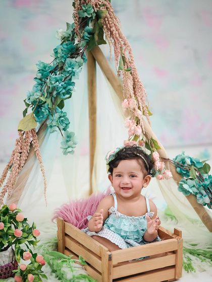 A happy baby in a floral teepee. This boho-chic setup combines natural elements with soft colors for a beautiful and trendy look.
