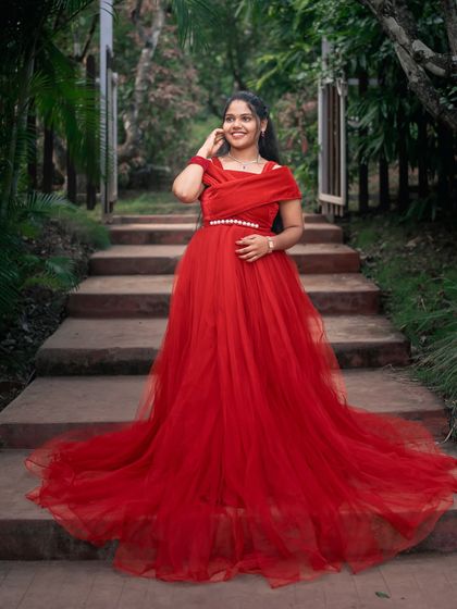 A beautiful solo portrait of the bride-to-be in a stunning red gown. The long train cascades down the stairs, creating a dramatic and elegant effect.