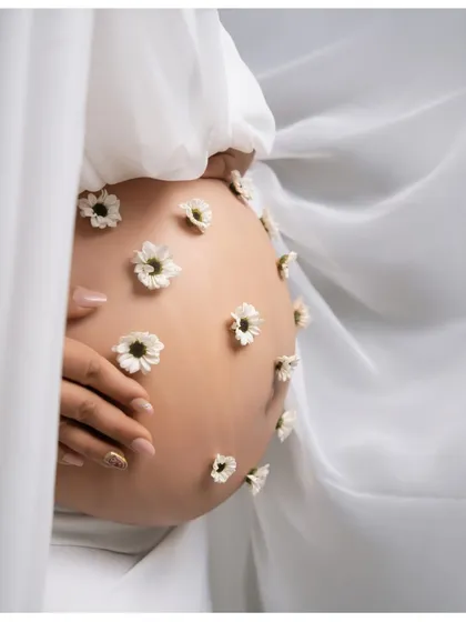 A close-up of the blooming bump. This detail shot shows the delicate daisies placed on the belly, a beautiful and creative way to symbolize the new life growing within.