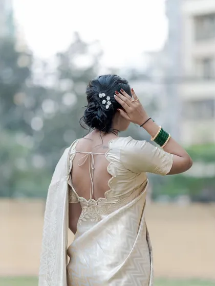 A view of the elegant low bun hairstyle, adorned with small white flowers, created for the naming ceremony.