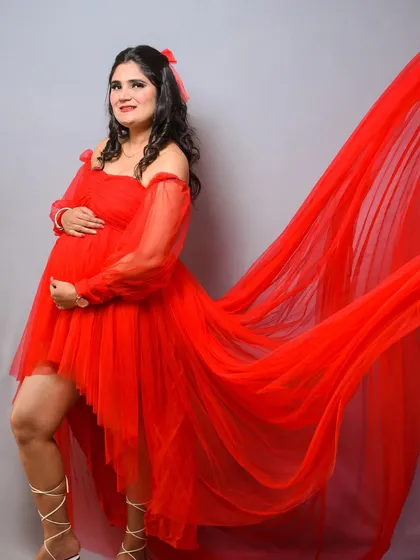 A bold and beautiful studio shot. The flowing red tulle of this gown creates a sense of drama and movement, resulting in a truly showstopping maternity portrait.