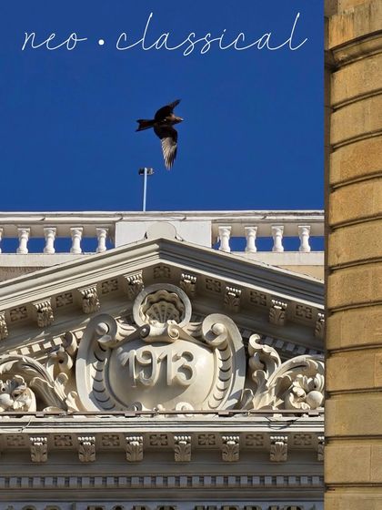 A neo-classical detail from 1913, with a bird caught in mid-flight against a brilliant blue sky. A perfect moment of symmetry and life.